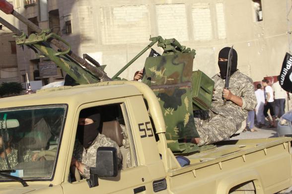 Các chiến binh phiến quân ngồi trên một xe quân sự khi tham gia lễ diễu binh trên đường phố ở Raqqa, Syria.