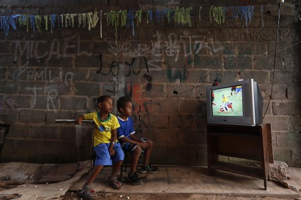 Các cậu bé ngồi xem một trận đấu tại World Cup 2014 qua tivi tại khu ổ chuột Varjao ở ngoại ô thủ đô Brasilia, Brazil.