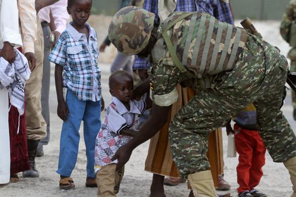 Một binh sĩ kiểm tra một em bé Hồi giáo trước khi cho phép tham gia lễ cầu nguyện tại một nhà thờ ở thủ đô Mogadishu, Somali.