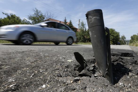 Ô tô đi qua một vỏ đạn trên đường ở ngoại ô Donetsk, Ukraine.