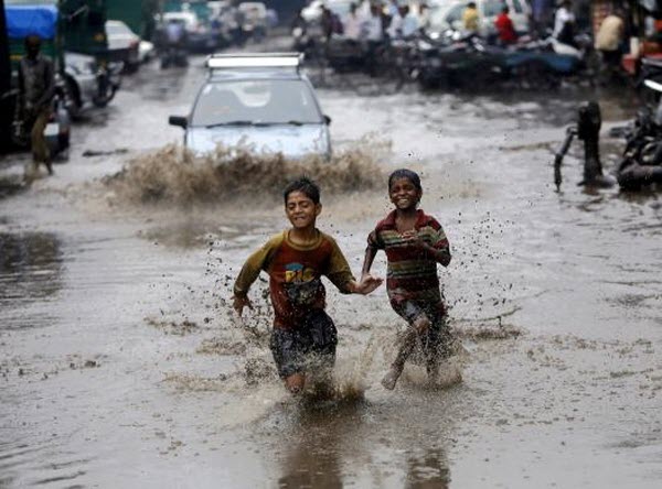 Các cậu bé chạy trên đường phố ngập nước lũ sau mưa lớn tại New Delhi, Ấn Độ.