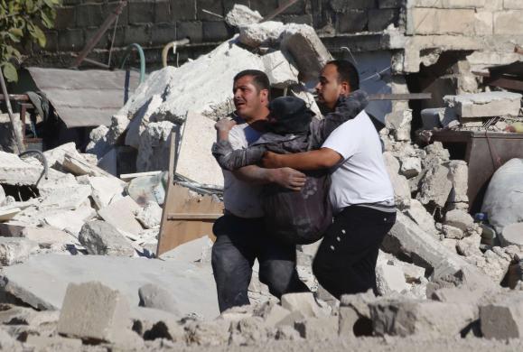 Những người đàn ông bế một phụ nữ bị thương rời khỏi hiện trường vụ không kích của quân đội chính phủ nhằm vào thành phố Aleppo, Syria.