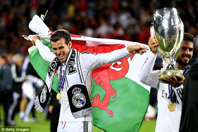 Proud Welshman: Bale shows off the Welsh flag on the pitch as Madrid players celebrated victory