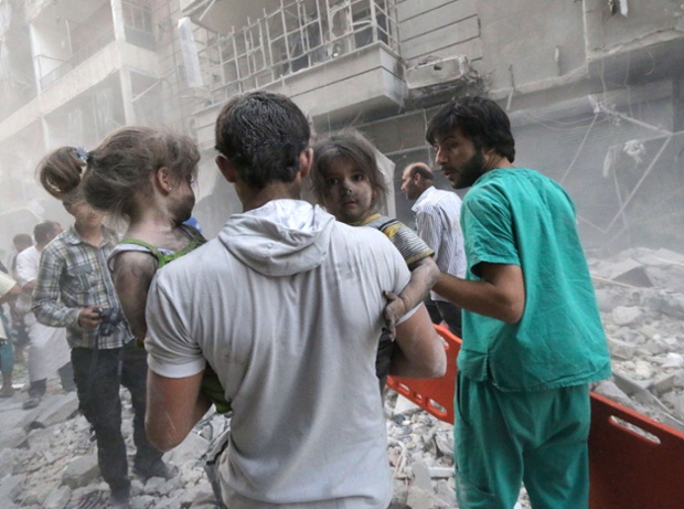 Người đàn ông bế hai bé gái phủ đầy bụi bẩn sau cuộc không kích của quân đội chính phủ nhằm vào thành phố Aleppo, Syria.