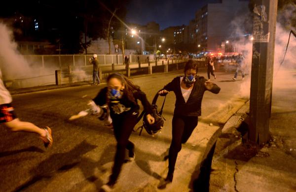 Người biểu tình chạy khỏi đạn hơi cay do cảnh sát chống bạo động bắn ra tại Rio de Janeiro, Brazil.