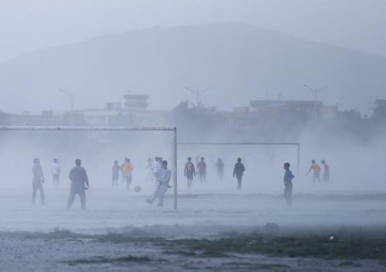 Mọi người chơi bóng đá trong bụi mù mịt ở Kabul, Afghanistan.