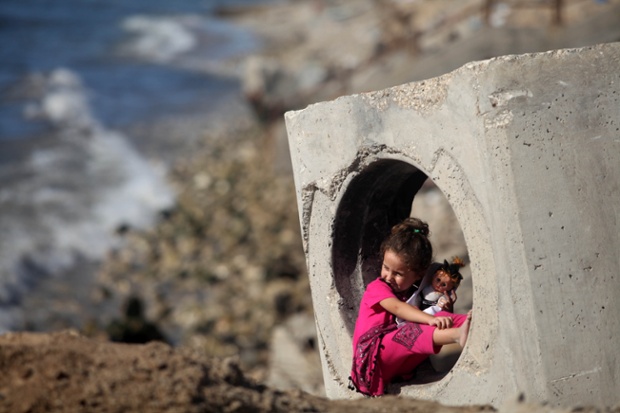 Một bé gái người Palestine ngôi chơi bên ngoài nhà gần bờ biển ở thành phố Gaza.