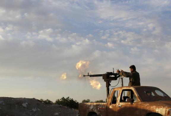 Một chiến binh phiến quân xả súng phòng không từ trên một chiếc xe bán tải ở Idlib, Syria.