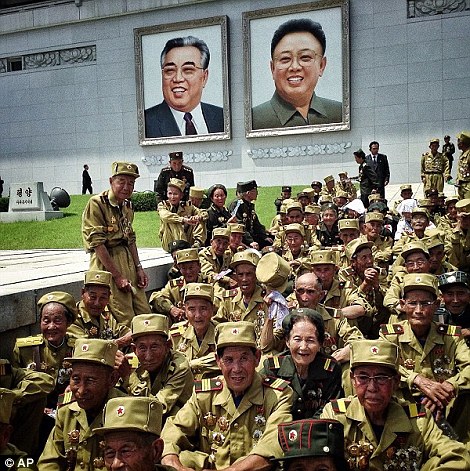 Cựu chiến binh Bắc Triều Tiên Chiến tranh Triều Tiên ngồi dưới bức chân dung của cố lãnh đạo Kim Il Sung và Kim Jong Il tại một cuộc diễu hành quân sự đại chúng để đánh dấu kỷ niệm 60 năm hiệp định đình chiến