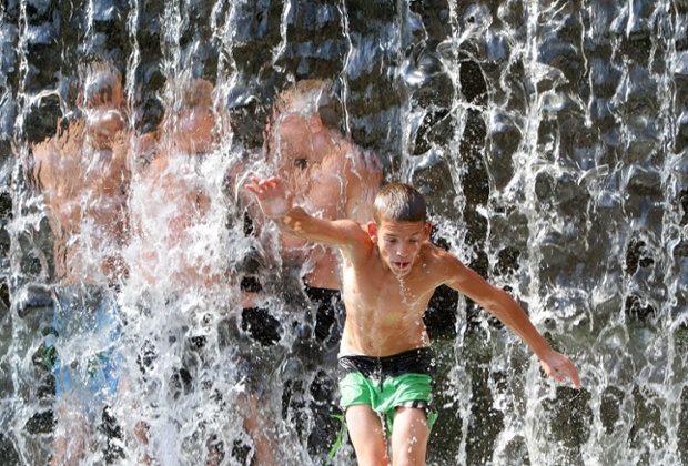 Cậu bé tắm dưới thác nước khi nhiệt độ ngoài trời tăng tới 33 độ C ở Vilnius, Lithuania.