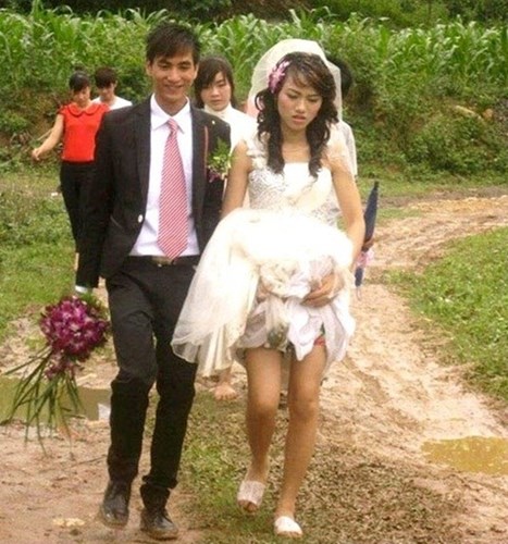 Cô dâu trong bức ảnh này dường như rất vất vả để vượt qua con đường xấu khi chân đi dép tổ ong, vén váy cao