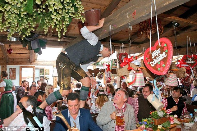 Munich goalkeeper Manuel Neuer clambers above some punters at Oktoberfest on Sunday