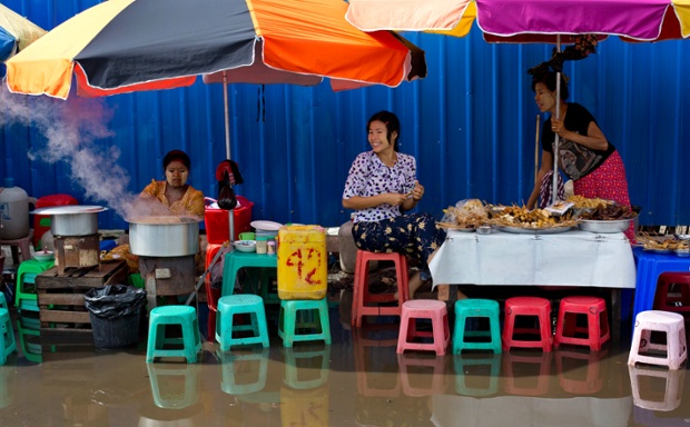 Người bán hàng chuẩn bị đồ ăn tại một góc phố bị ngập lụt ở thành phố Rangoon, Myanmar.