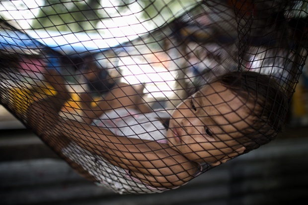 Em bé nằm nghỉ ngơi trên võng cạnh đường phố ở Manila, Philippines.