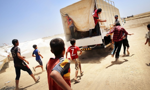 Những người tại trại tị nạn Khazair, gần thành phố Mosul ở Iraq, đuổi theo một xe phân phát lương thực của Hội Trăng lưỡi liềm Đỏ.