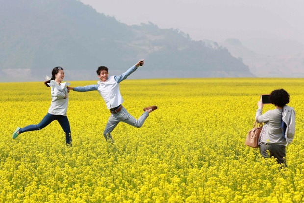 Du khách chụp ảnh trên cánh đồng hoa cải nở vàng tại thị trấn Khoan Điện, tỉnh Liêu Ninh, Trung Quốc, gần biên giới với Triều Tiên.