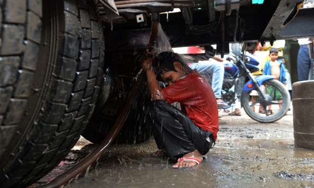 Một cậu bé tắm dưới vòi phun của xe chở nước ở New Delhi, Ấn Độ.