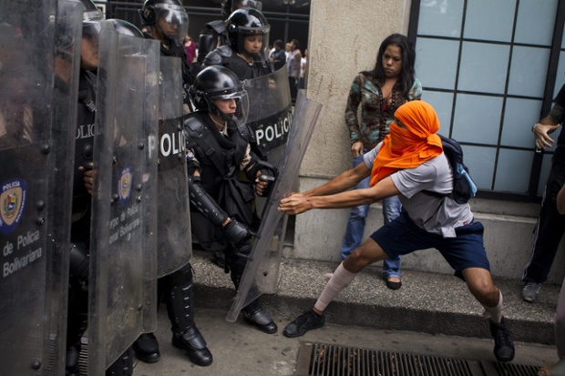 Một người biểu tình đụng độ với lực lượng cảnh sát chống bạo động ở Caracas, Venezuela.