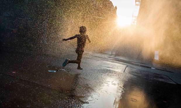 Một bé gái chạy qua máy phun hơi nước trên sân chơi tại khu phố Brooklyn, New York, Mỹ.