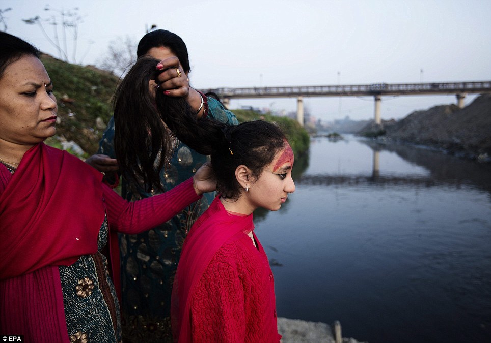 Purna Shova (L) cởi tóc của con gái bà Kumari Samita Bajracharya (R) sau khi hoàn thành 12 ngày lễ Gufa, tại sông Bagmati trong Patan, Nepal, ngày 07 tháng 3 năm 2014