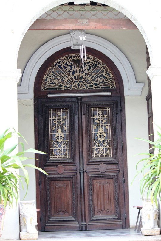 Lối vào có hai lớp cửa, bên trong của gỗ và bên ngoài của cuốn sắt được đẩy lên. Đây là một trong những nét đặc trưng kiến trúc Pháp những năm đầu thế kỉ XX.