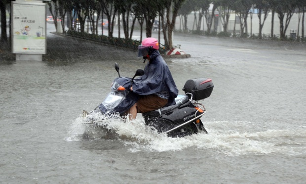 Một người đi xe máy trên đường phố ngập nước khi bão Matmo  gây mưa lớn tại thành phố Tấn Giang, Trung Quốc.