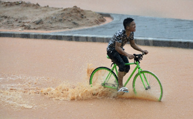 Một người đàn ông vất vả đạp xe trên đường phố ngập lụt ở thành phố Thâm Quyến, tỉnh Quảng Đông, Trung Quốc.