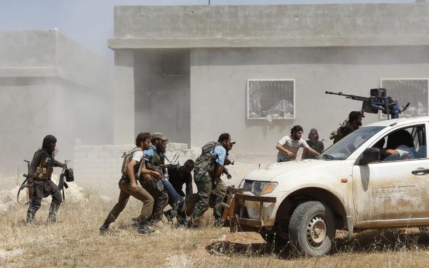 Các chiến binh phiến quân giúp đồng đội bị thương trong cuộc giao tranh với quân đội chính phủ ở thị trấn Morek, tỉnh Hama, Syria.