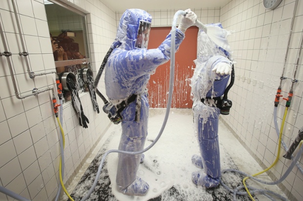 Hai thành viên của đội y tế tại bệnh viện Charite ở Berlin, Đức, biểu diễn quy trình khử nhiễm tại khu vực điều trị bệnh ebola của bệnh viện.