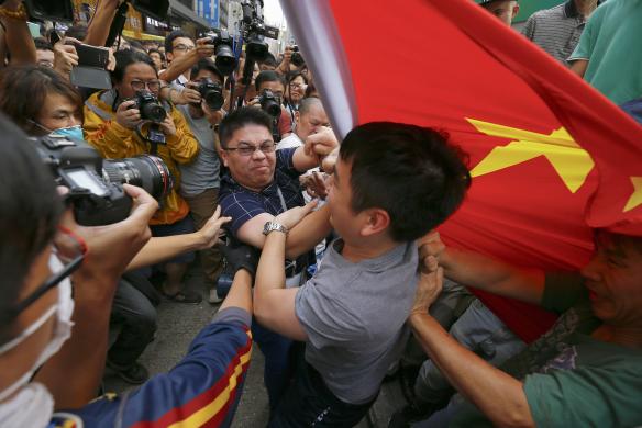 Người biểu tình hỗn chiến với một người đàn ông cầm cờ Trung Quốc tại khu phố thương mại Mongkok, Hong Kong.