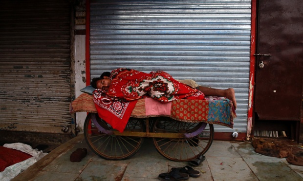 Những người lao động ngủ trên xe kéo tay bên ngoài một cửa hàng ở Dharavi, Ấn Độ.