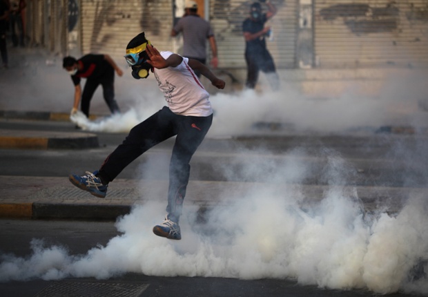 Người biểu tình chống chính phủ nhảy lên để tránh lựu đạn hơi cay do cảnh sát ném trong cuộc đụng độ ở Sitra, Bahrain.