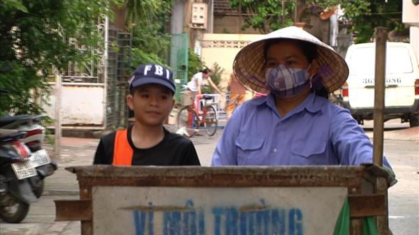 Quang Anh đẩy xe rác cùng với mẹ