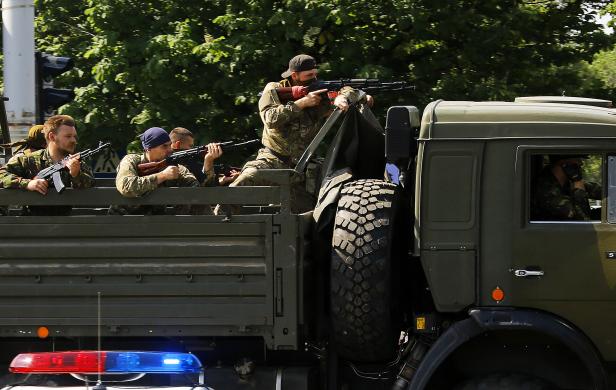 Một xe tải quân sự chở các chiến binh thân Nga vượt qua một chốt kiểm tra cảnh sát, hướng tới sân bay ở thành phố Donetsk, Ukraine.