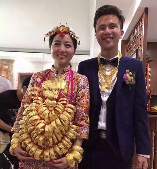 Ngày hôm qua, cư dân mạng Việt Nam liên tục chia sẻ hình ảnh về 1 cô dâu đeo đầy vòng vàng trong lễ cưới. Số vòng cưới của cô nhiều và nặng tới mức cô đã phải dùng tay đỡ nhẹ toàn bộ chuỗi dây đeo vòng vàng này.