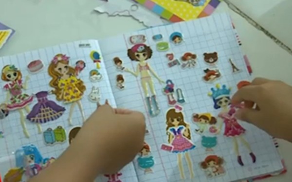 Với màu sắc bắt mắt, hình dáng đa dạng và giá rẻ, những miếng dán hoạt hình trở thành đồ chơi yêu thích của trẻ em - (Ảnh cắt từ clip).