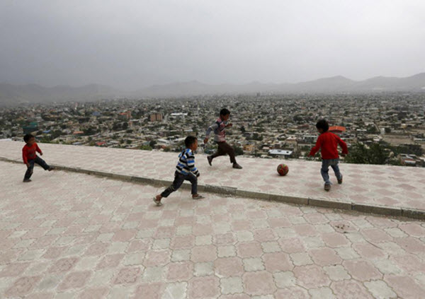 Các cậu bé chơi đá bóng trên một đỉnh đồi nhìn ra Kabul, Afghanistan.