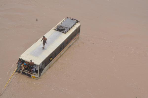 Nhân viên cứu hộ cố gắng giải cứu hành khách bị mắc kẹt trong một chiếc xe bus giữa vùng ngập lụt ở Gujarat, Ấn Độ.