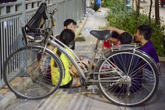 Một nhóm bạn trẻ dùng xe đạp chắn ngang đường để bày đồ ăn uống.
