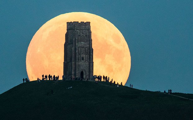 Mọi người ngắm “siêu trăng từ trên một đỉnh đồi ở Glastonbury Tor, Anh.