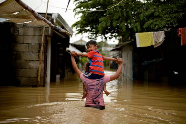 Người phụ nữ cõng con trai qua một con đường ngập ở Calumpit ngoại ô Manila, Philippines.