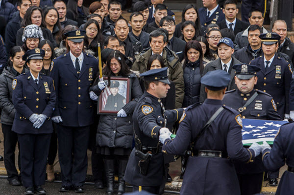 Vợ của cảnh sát Wenjian Liu ôm một bức ảnh chồng trong lễ tang của anh ở Brooklyn, New York, Mỹ. Wenjian Liu đã bị bắn chết trong xe tuần tra cùng người đồng nghiệp là Rafael Ramos vào hồi cuối tháng 12 năm ngoái.