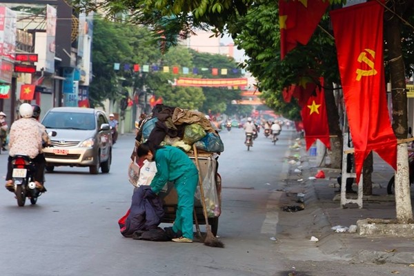 Xe rác của cô lao công đã đầy ắp nhưng đường phố vẫn còn quá nhiều rác cần dọn - (Nguồn: Vietnam Streetlife Photography).