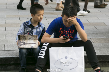 
Trẻ em ngồi trông hàng bên ngoài trung tâm thương mại để đợi người lớn.
