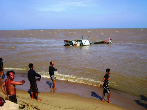 Ngư dân đang tìm cách đưa vào bờ một tàu cá bị sóng đánh chìm trên biển Phú Yên Ảnh: HỒNG ÁNH