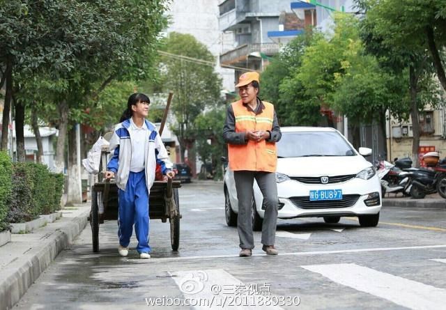 Cô bé cười rất tươi khi đang giúp mẹ làm công việc dọn dẹp vệ sinh đường phố. (Nguồn: CCTV News)
