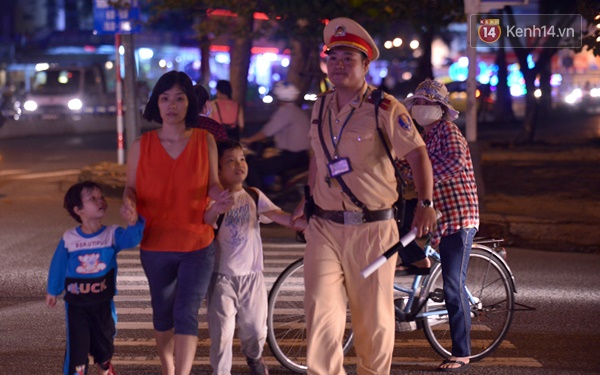 Chiến sĩ CSGT trẻ dắt người dân sang đường trong lúc phân làn giao thông - (Ảnh: Hoàng Anh)