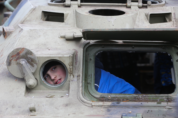  Cậu bé nhìn qua cửa sổ chiếc BTR-80 tại cuộc triển lãm.