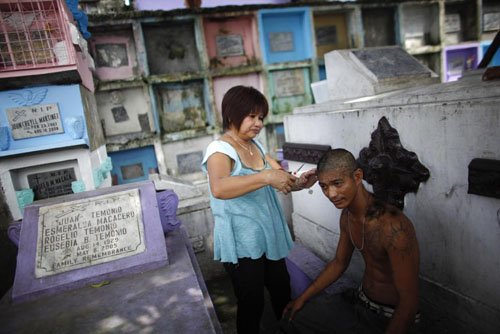 
Người dân cắt tóc ngay cạnh những ngôi mộ được xếp chồng lên nhau tại một nghĩa trang ở phía bắc thành phố Manila. Đây là nơi chôn cất của hàng trăm ngàn tử thi, nằm trong những ngôi mộ đa phần làm bằng bê tông hình hộp chữ nhật nằm lộ thiên.
