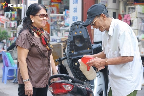 
Vừa đổ xăng cho khách, ông vừa trò chuyện với bà hàng xóm sống ở gần đó.
